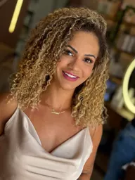 Cliente com cachos volumosos e mechas douradas