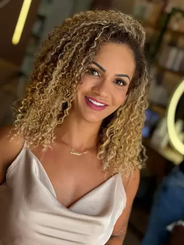 Cliente com cachos volumosos e mechas douradas