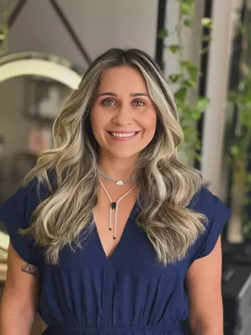 Cliente com cabelo loiro platinado iluminado e ondulado