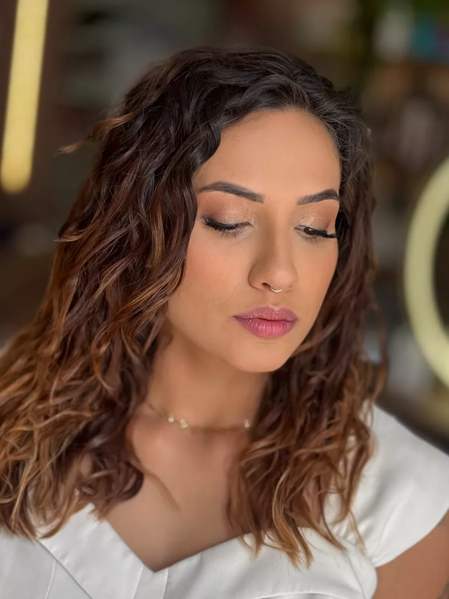 Cliente morena com ondas castanhas e pontas iluminadas em tom de caramelo