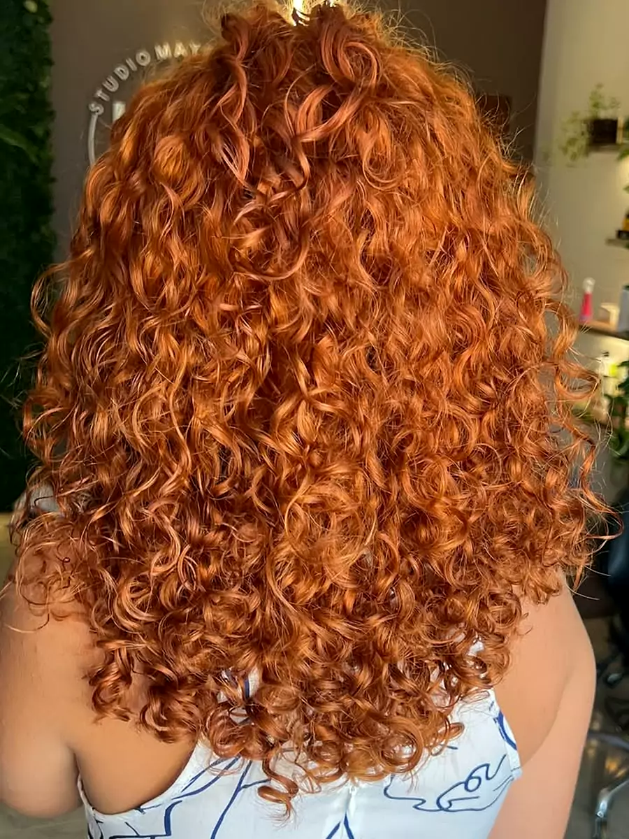 Cliente de costas com cachos longos em ruivo cobre, depois de cor e corte no studio